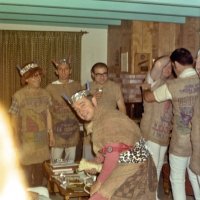 Early 1971 - Dress rehearsal for the District 4-C4 Convention in May at a member’s home - Near window are, L to R,  Bill Tonelli, Charlie Bottarini, Jack Parodi, and Frank Ferrera in front, while Art Blum helps another member fit his burlap sack to the right.