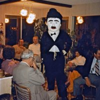 2/4/83 - Convention Prep, at a member’s residence - Handford Clews (guess) modeling Charlie Chaplin costume. Starting at lower left and going around room: Charlie Bottarini, Sam San Filippo, Estelle Bottarini, Irene Tonelli, (by window) Ron Faina, Les Doran, (right side of costume) and Emily & Joe Farrah.