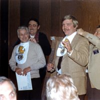 1/19/83 - New Member Induction & Ladies’ Night, L & L Castle Lanes, San Francisco - Les Doran & Drake Woznick - Left: Handford Clews behind Les Doran; right: Joe Farrah behind Drake Woznick. Sponsors tying Baby Lion bibs on their sponsorees. It was tradition, at the time, that newly inducted Lions were the Baby Lion bib at meetings until another person was inducted into the club.