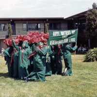 5/11/85 - District 4-C4 Convention, El Rancho Tropicana, Santa Rosa - Costume Parade - Members in costume walking in a bunch - Claire Holl can be seen on left, with Irene Tonelli’a face just peeking in near the sign.