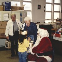 12-20-02 - Mission Education Center Christmas with Santa, Mission Education Center, San Francisco - Joe Farrah and Al Gentile feed Santa presents as each student comes forward with anticipation to accept them. Santa’s assistant smiles her approval.