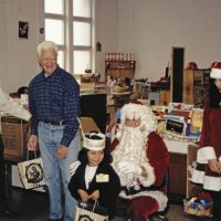 12-20-02 - Mission Education Center Christmas with Santa, Mission Education Center, San Francisco - A student impatiently poses with Santa after receiving her present. On the left, Joe Farrah and Al Gentile  pause their duties, and Santa’s assistant smiles for the camera.