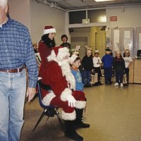 12-20-02 - Mission Education Center Christmas with Santa, Mission Education Center, San Francisco - The last student in the class poses with Santa after receiving his present. On the left, Al Gentile starts looking for the next group of presents; the other students in the class wait in the background.
