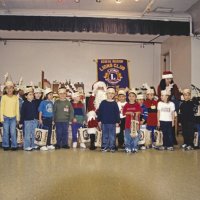 12-20-02 - Mission Education Center Christmas with Santa, Mission Education Center, San Francisco - Eighteen students in the class all pose with Santa after receiving their presents. Joe Farrah stands on teh left, their teacher on the right. Santa’s assistant helps a couple of students line up for the camera.