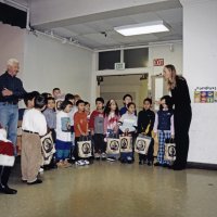 12-20-02 - Mission Education Center Christmas with Santa, Mission Education Center, San Francisco - All the students in the class having gotten their gifts, take instruction from their teacher, on right, on what to do next. On the left, Santa, his assistant, the teacher’s aid, and Al Gentile, also listen.