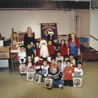 12-20-02 - Mission Education Center Christmas with Santa, Mission Education Center, San Francisco - Students pose with Santa after receiving their presents. with them are their teacher, in the group on left, her assistant, on the left, and Santa’s assistant. Dr. Mehandra Dave and Sheriar Irani stand on the left.