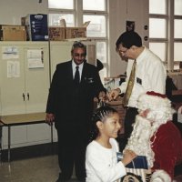 12-20-02 - Mission Education Center Christmas with Santa, Mission Education Center, San Francisco - A student happly leaves Santa all smiles while Dr. Mehandra Dave, left, and Sheriar Irani get the next gift bag ready.