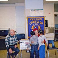 12/17/04 - Mission Educational Center - Bill Graziano helps Santa present gifts to students while Joe Farrah stands by in support.