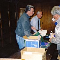 12/15/05 - MEC Christmas at Lion Charlie Bottarini‘s basement on Moscow St. - L to R: Lions Bob Fenech, Ward Donnelly, and Joe Farrah setting up gifts to be distributed to students at the next day‘s Christmas Party at the Mission Educational Center. Lion Aaron Straus in hiding behind Lion Joe.