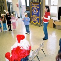 12/15/06 - Christmas at Mission Educational Center, Police Officer “Nacho” Martinez as Santa - Santa, and others, look on as students and their teacher sing a song for them. Bill Graziano is last on upper right.