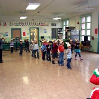 12/17/10 - Annual Christmas with Santa - Mission Education Center, San Francisco - Santa with his elf helpers look on as the kindergarten class arrives. Principal Deborah Molof, on the right, guides them into the room as her assistant takes photos.