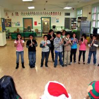 12/17/10 - Annual Christmas with Santa - Mission Education Center, San Francisco - A class, perhaps fourth graders, performs their musical number using recorders, as Santa and his Eleves look on.