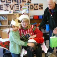 12/16/11 - Annual Christmas with Santa - Mission Education Center, San Francisco - Ms. Linda as Santa, with her dog Emma - Each student takes turns posing with Santa. Al Gentile, on right, hands Santa a gift for each student.