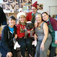 12/16/11 - Annual Christmas with Santa - Mission Education Center, San Francisco - Ms. Linda as Santa, with her dog Emma, and Jackie Cash as her Elf - A teacher, her assistant, and a cafeteria helper take time to pose with Santa. Al Gentile is sorting gift bags in the background.