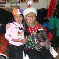 12/16/11 - Annual Christmas with Santa - Mission Education Center, San Francisco - Ms. Linda as Santa, with her dog Emma, and Jackie Cash as her Elf - Each student takes turns posing with Santa. Al Gentile in the background.
