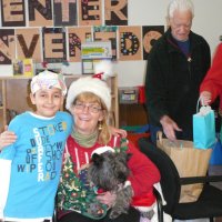 12/16/11 - Annual Christmas with Santa - Mission Education Center, San Francisco - Ms. Linda as Santa, with her dog Emma, and Jackie Cash as her Elf - Each student takes turns posing with Santa. Al Gentile handling gift bags in the background.