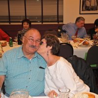 12-15-16 - Club Christmas Party, Basque Cultural Center, South San Francisco - Kathy Salet giving her husband George a Christmas kiss; background, L to R: two guests, Bob Fenech, Leona Wong, and Bob Lawhon (back to camera).