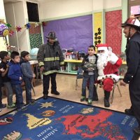 12-15-16 - Christmas with Santa with the help of Los Bomberos Firefighters, Mission Education Center, San Francisco - Los Bomberos Firefighters help Santa hand presents to each student after which, they get their picture taken with Santa.