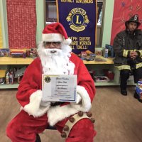 12-15-16 - Christmas with Santa with the help of Los Bomberos Firefighters, Mission Education Center, San Francisco - Santa displays the certificate of thanks from the Geneva-Excelsior Lions Club.