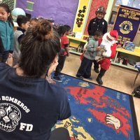 12-15-16 - Christmas with Santa with the help of Los Bomberos Firefighters, Mission Education Center, San Francisco - From the camera’s point of view - a student receives their gift from Santa.