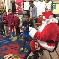12-15-16 - Christmas with Santa with the help of Los Bomberos Firefighters, Mission Education Center, San Francisco - A students admires his gift from Santa as others wait their turn.