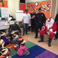 12/21/17 - Christmas with Santa, Mission Educational Center - San Francisco Firemen stand nearby with Santa as he talks with school children patiently waiting for their turn with Santa.