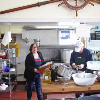 2-18-17 - 32nd Annual Crab Feed, Mariposa Hunters Point Yacht Club, San Francisco - In teh kitchen are, L to R, Viela du Pont, helper, and Bob Fenech.