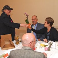 06/20/18 - 69th Installation of Officers, Italian American Social Club, San Francisco - Outgoing Lion President Sharon Eberhardt presenting Kathy Salet, incoming President‘s wife, with an orchid and thank you for lending her husband to the club this coming year. L to R: Lion Sharon Eberhardt, Lion George and Kathy Salet. Lion Bill Graziano has his back to camera.