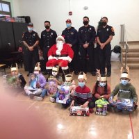 12-10-21 - Mission Education Center Christmas with Santa @ MEC, San Francisco - Students, with their gifts, pose with Santa and the Los Bomberos Firefighters.