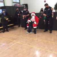 12-10-21 - Mission Education Center Christmas with Santa @ MEC, San Francisco - A little girl hugs Santa after receiving her gift as others look on.