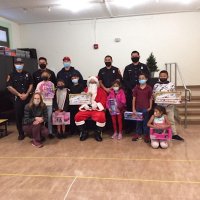 12-10-21 - Mission Education Center Christmas with Santa @ MEC, San Francisco - A teacher and her students, with their gifts, pose with Santa and the Los Bomberos Firefighters.