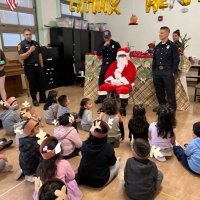 12-9-22 - Mission Education Center Christmas with Santa, San Francisco - Students listening to a Los Bomberos member as he talks to them.