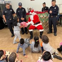 12-9-22 - Mission Education Center Christmas with Santa, San Francisco - A little girl carefully accepts her gift from Santa.