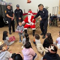 12-9-22 - Mission Education Center Christmas with Santa, San Francisco - A student rushes back to his place after receiving his gift from Santa as other students wait patiently.