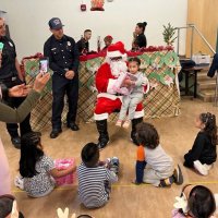 12-9-22 - Mission Education Center Christmas with Santa, San Francisco - A litle girl shyly poses with Santa after receiving her gift.