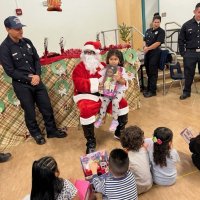 12-9-22 - Mission Education Center Christmas with Santa, San Francisco - A student poses with Santa after receiving her new baby doll.