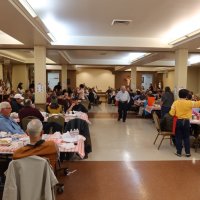 2-25-23 - 36th Annual Crab Feed - St. Philip the Apostle Church, San Francisco - A short while before diner served; Bob Lawhon walking down center; Suzie Moy, yellow shirt on right, slinging raffle tickets.